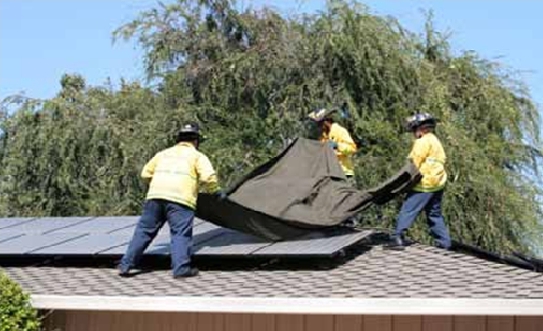 Firemen covering solar panel with tarp